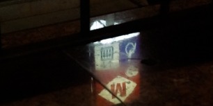 A still image of the reflection of a metro sign.