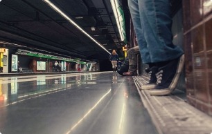 Foto de una anden de la L3 desde el suelo, en primer plano las piernas de una persona sentada
